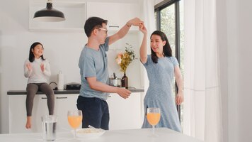 Happy young asian family listen to music and dancing after breakfast at home. attractive japanese mother father and child daughter are enjoying spending time together in modern kitchen in the morning.