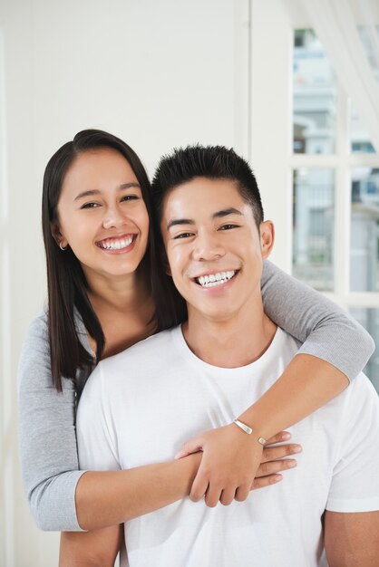 Happy young Asian hugging and looking at camera