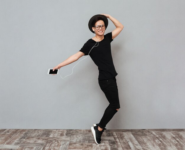 Happy young asian man standing isolated over grey wall