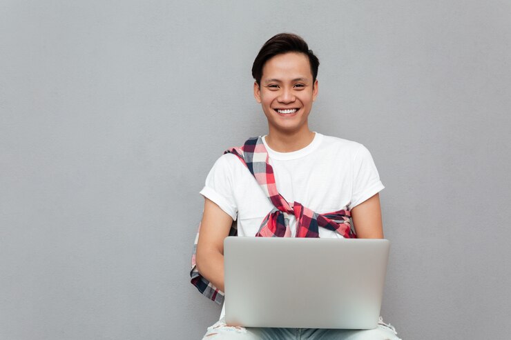 Free Photo happy young asian man using laptop