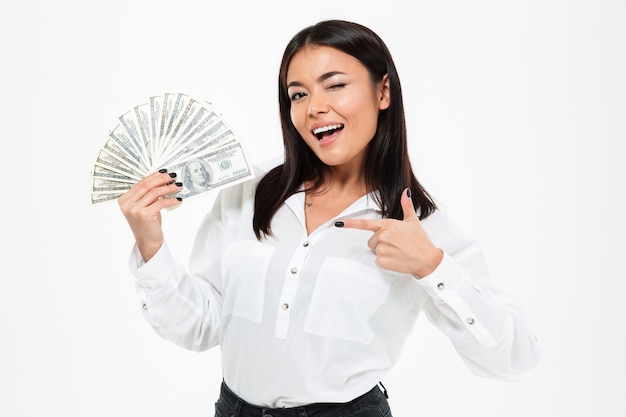 Happy young asian woman holding money pointing.