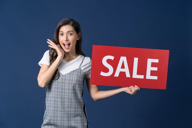 Happy young asian woman holding sales banner and looking surprise to sales paper Premium Photo