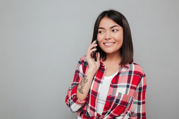 Happy young asian woman isolated over grey wall