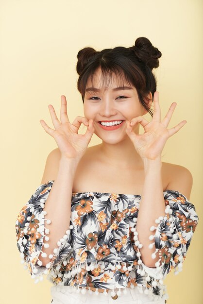 Счастливая молодая азиатская женщина представляя в студии с открытой улыбкой и смешными жестами рукой