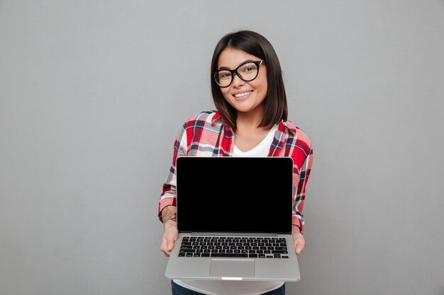랩톱 컴퓨터의 표시를 보여주는 행복 한 젊은 아시아 여자.