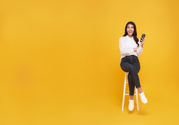 Happy young Asian woman showing mobile phone While her sitting on white chair