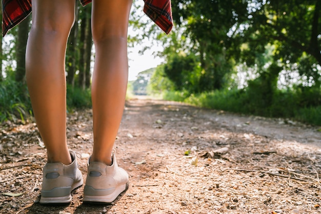 Happy young Asian woman traveler with backpack walking in forest.