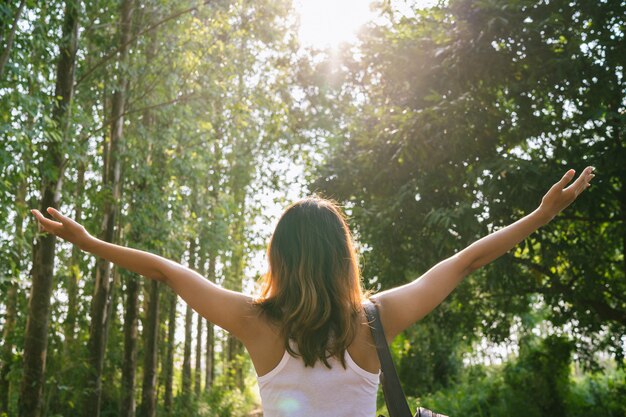 Happy young Asian woman traveler with backpack walking in forest. 