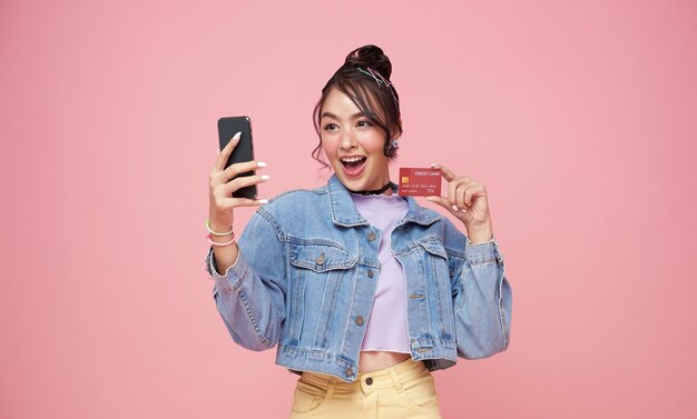 携帯電話とpingの背景で隔離のクレジットカードを使用して幸せな若いアジアの女性
