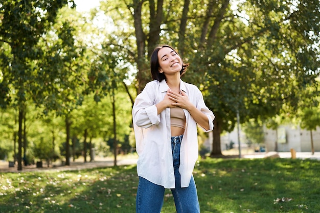 Foto gratuita felice giovane donna asiatica che cammina da sola ballando e cantando nel parco sorridendo gente spensierata e lifest