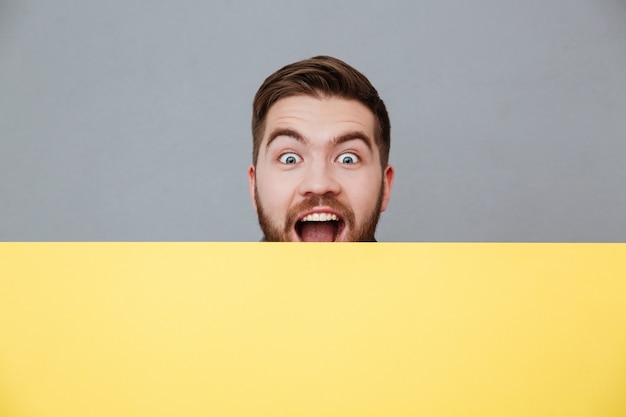 Happy young bearded man holding blank board