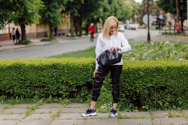 Happy young beautiful woman using her smart phone walking on the city street