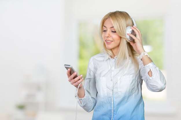 Happy young blonde woman listening to music