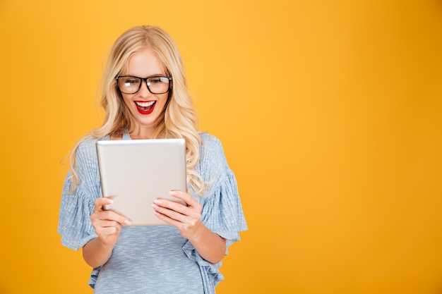 Happy young blonde woman using tablet computer.