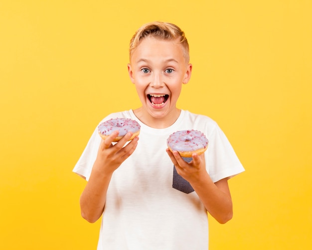 Happy young boy holding doughnuts