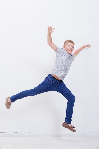 Бесплатное фото Счастливый мальчик прыгает на белом фоне