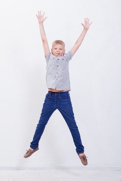 Happy young boy jumping over a white background