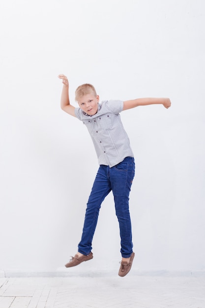 Happy young boy jumping  on white wall