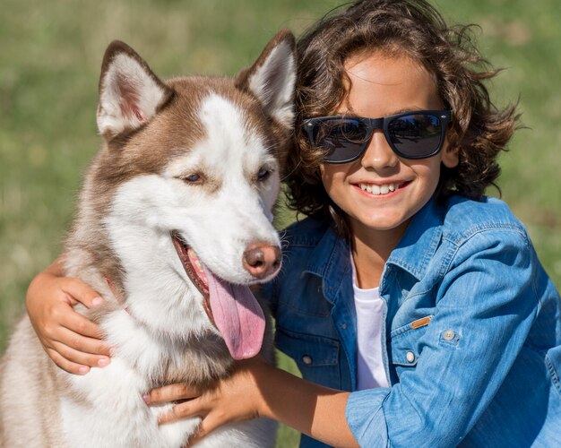 Happy young boy posing with dog while at the park