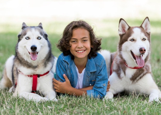 Happy young boy posing with his dogs at the park