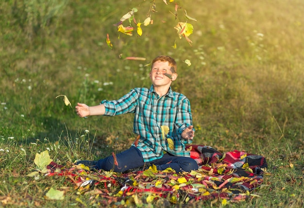 Happy young boy throwing autumn leaves in the air