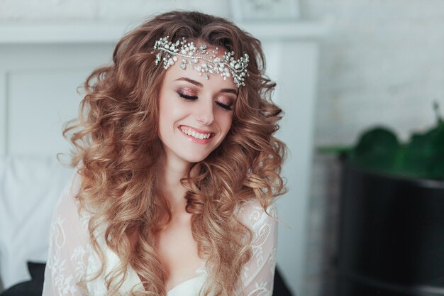 Happy young bride in tiara and lingerie laughing. Close portrait.