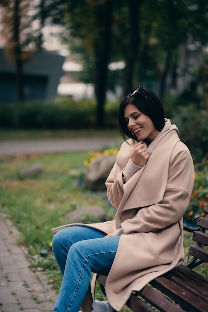 Happy young brunette sitting on a park bench