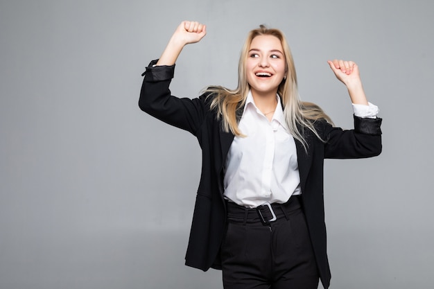 Happy young business woman doing winner gesture, keeping eyes closed posing isolated