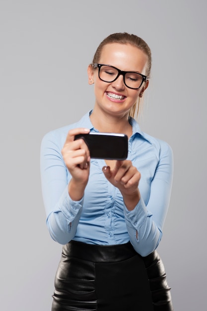 Happy young business woman text messaging on smart phone