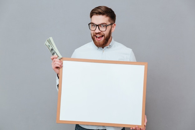 Happy young businessman holding blank board and money