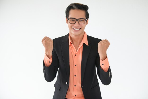 Happy young businessman showing winning gesture