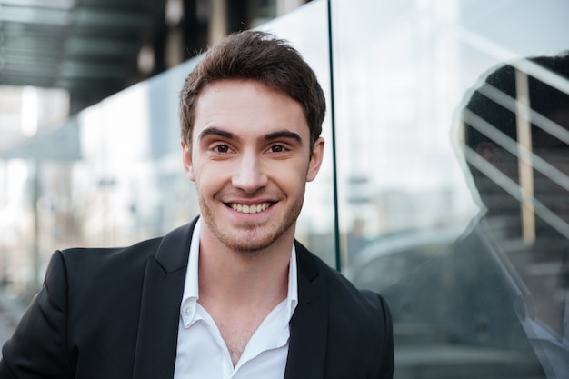 Happy young businessman walking near business center