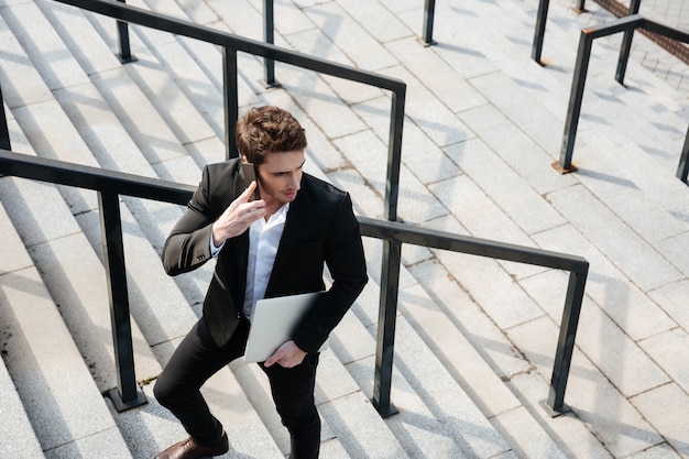 Happy young businessman walking outdoors.