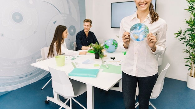 Happy young businesswoman holding flat paper globe