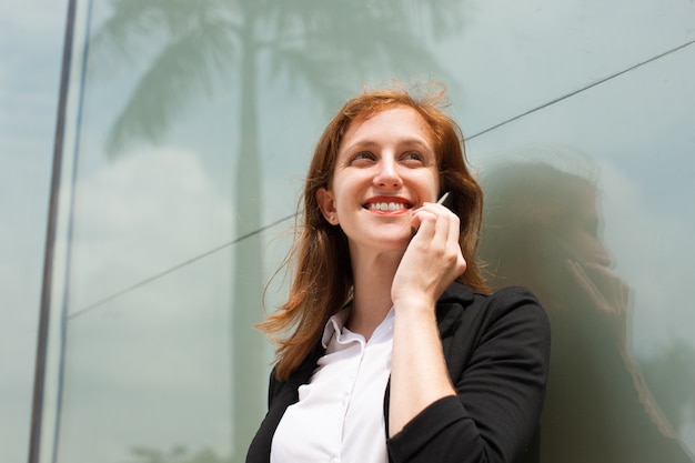 Happy young businesswoman talking on cellphone