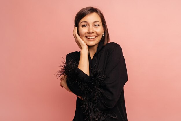 Happy young caucasian brunette woman with smile on her face looks at camera on pink background Lifestyle concept