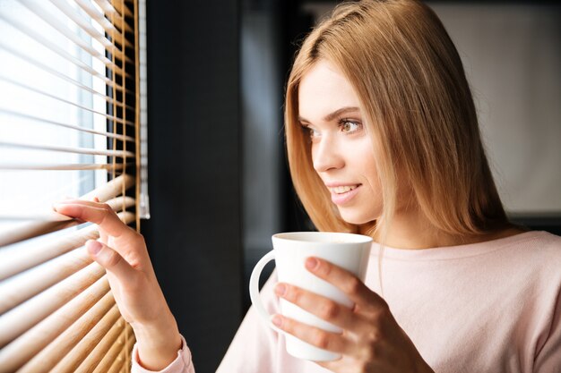 カフェに立って幸せな若い陽気な女性