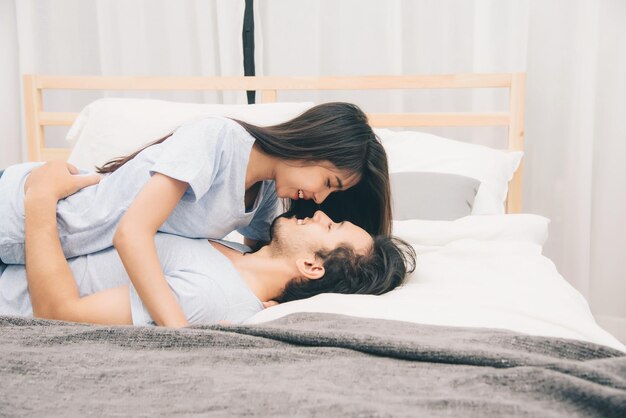 寝室のロマンチックな瞬間のベッドで幸せな若いカップル