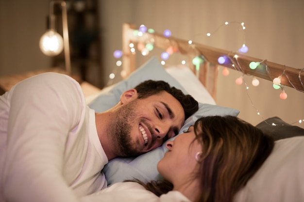 Free photo happy young couple cuddling in bed