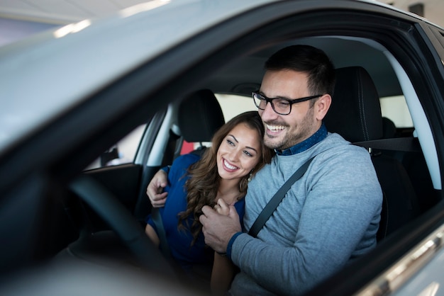 彼らの真新しい車を楽しんで幸せな若いカップル