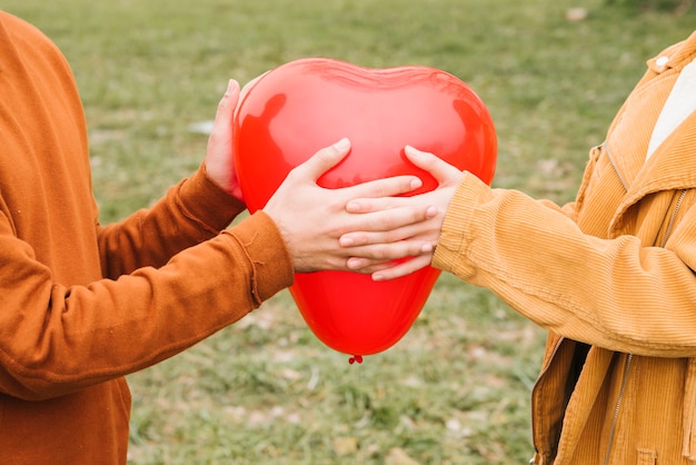 Happy young couple holding heart-shaped balloon