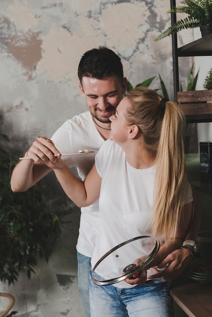 Free photo happy young couple holding mushroom slice on spatula