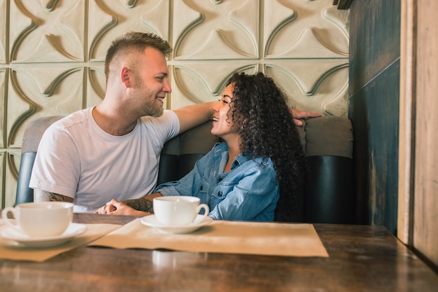 Free photo happy young couple is drinking coffee and smiling while sitting at the cafe