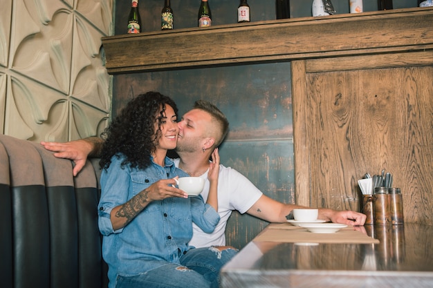 Happy young couple is drinking coffee and smiling while sitting at the cafe