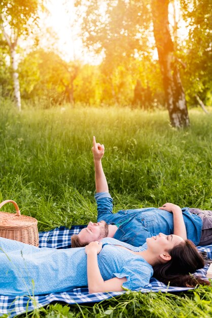 Happy young couple looking at sky while lying on blanket in nature