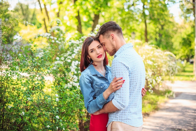 Happy young couple at park standing and laughing on the bright sunny day