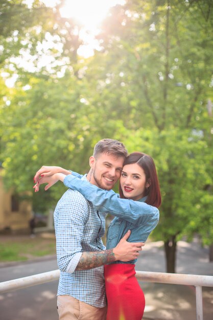 Happy young couple at park standing and laughing on the bright sunny day