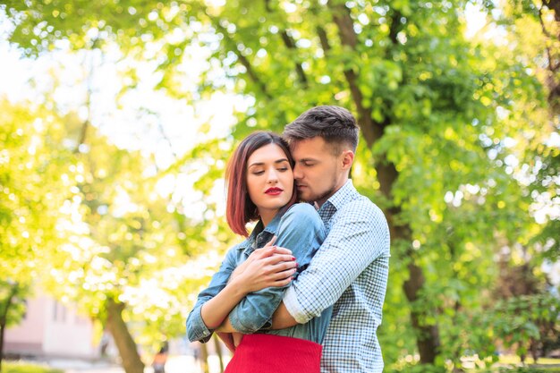 Happy young couple at park standing and laughing on the bright sunny day