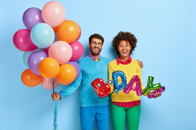 счастливая молодая пара на вечеринке позирует с воздушными шарами