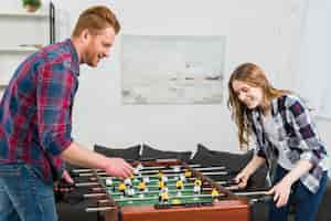 Foto gratuita giovani coppie felici che giocano il gioco di calcio della tavola di calcio a casa